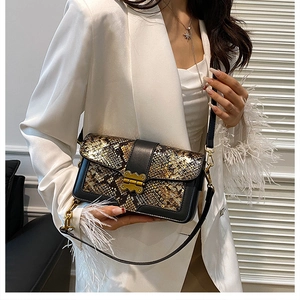 Detail of snake skin pattern texture and golden butterfly clasp on crossbody bag