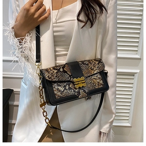Detail of vintage snake print patchwork crossbody bag with decorative gold chain strap