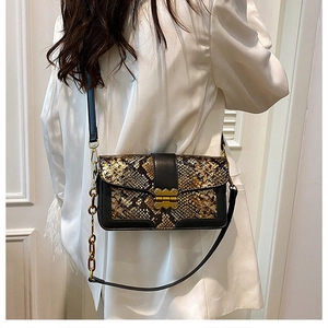 Detailed view of vintage snake skin pattern shoulder bag with a gold metal clasp on a model
