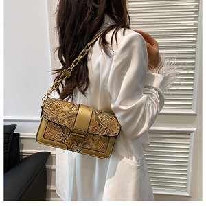 Detail of vintage yellow snakeskin handbag with gold metal lock and chain strap