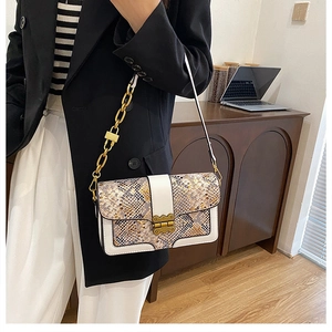 Detail of snakeskin textured handbag with gold chain strap and vintage metal clasp lock