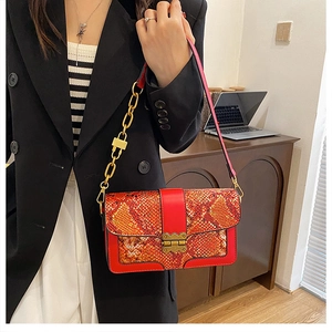 Detail of red snake pattern handbag with gold metal lock and chunky chain strap
