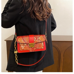 Detail of red snake pattern handbag with vintage gold buckle and metal chain strap