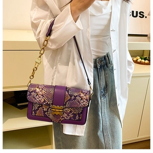 Detail of purple snake skin crossbody bag with gold buckle and chain strap on a model