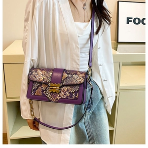 Detail of purple snake skin pattern handbag with vintage gold metal lock and leather strap