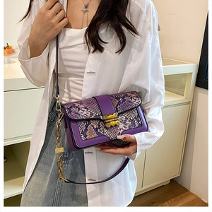 Detail of purple snakeskin patchwork handbag with gold metal clasp and chain strap