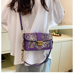 Detailed side view of purple snakeskin textured crossbody bag with gold hardware buckle