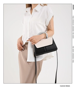 Detail of two-tone handbag with silver metal handle and adjustable leather strap