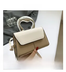 Detail of a color-block small square bag with silver metal handle and beige strap