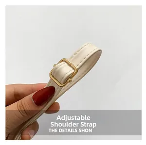 Detail of cream leather adjustable strap with golden buckle and fine stitching