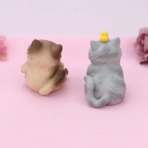 Rear view detail of cute brown and grey resin cat figurines with a tiny yellow bird
