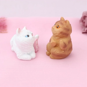 Detailed view of realistic resin cat figurines in white and orange for cake or car decor