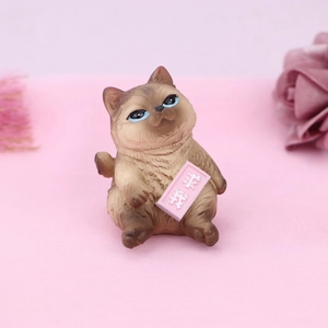 Detail of cute brown resin cat figurine holding a pink sign with a funny text design