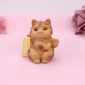 Close-up of resin cat ornament with yellow sign featuring funny Chinese text