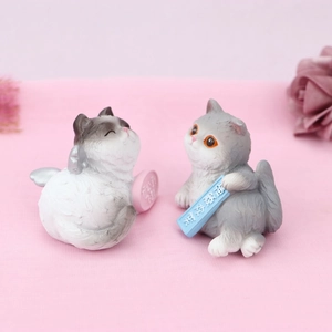 Close-up of cute resin cat figurines with lucky charms on pink textured background
