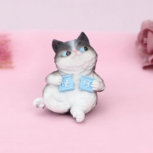 Close-up of cute grey and white resin cat figurine with blue eyes and playful signs