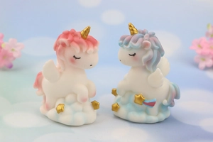 Detail of pink and blue unicorn resin figurines on golden star cloud bases