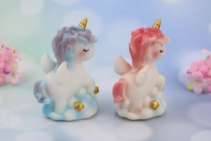 Macro detail of blue and pink unicorn figurines resting on cloud bases with gold stars