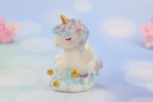 Close-up of unicorn cake topper on blue cloud base with gold star details
