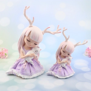 Dettaglio di due statuine fatate in resina con corna di cervo e abiti da balletto viola