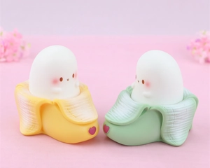 Close-up of cute banana ghost night lights in yellow and green colors on pink background