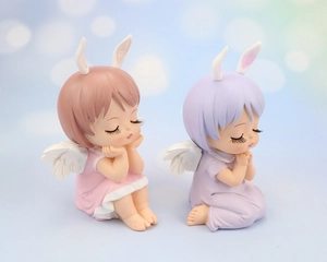 Close-up of cute pink and purple sleeping angel girl resin figurines with rabbit ears
