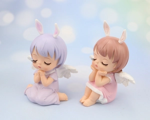 Close-up of cute resin angel girl figurines with rabbit ears and wings for cake decoration