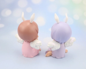 Detail of cute angel girl figurines with rabbit ears and wings in pink and purple colors