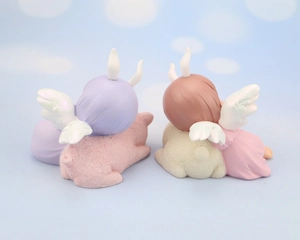 Rear view of two cute angel girl figurines with wings on pastel bases for cake decor