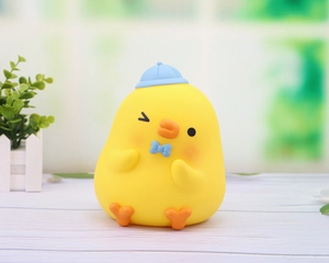 Close-up of a cute yellow duck piggy bank with a blue hat and bow tie on a wooden surface
