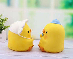 Detail of two cute yellow duck piggy banks wearing sun hats with matte vinyl texture