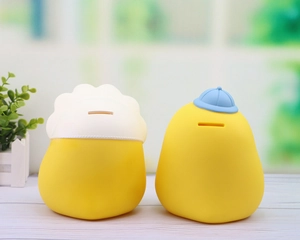 Detail of coin slots on the back of two cute yellow duck piggy banks for children