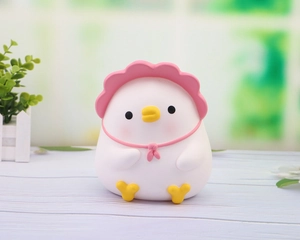 Close-up of cute white chick figurine with pink hat and bow on white wooden table