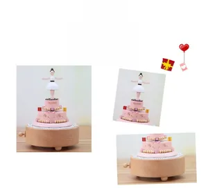 Detail of wooden music box with rotating ballerina on a pink tiered cake