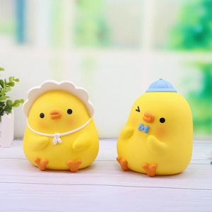 Cute yellow duckling coin banks with lace hat and blue bow tie in outdoor setting