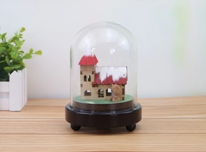 Close-up of winter snow scene music box with a miniature red roof cabin and small brown bear