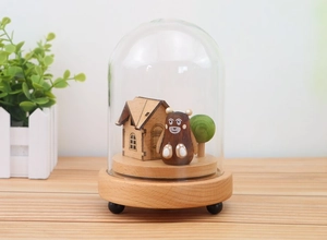 Detail of wooden music box showing a small house, bear and tree inside a glass dome