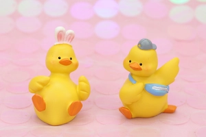 Close-up of cute yellow duck car ornaments with bunny ears and a baseball cap