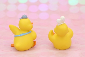Rear view of cute yellow duck figurines with mini hats and bags on a bokeh background