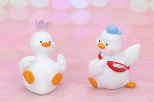 Close-up of cute white duck figurines with rabbit ears and a blue cap for car decor
