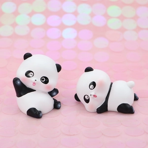 Close-up of two cute panda figurines for cake decoration on pink glitter background