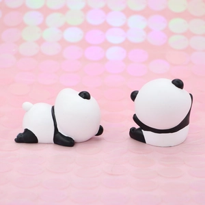 Close-up of two cute panda figurines for cake decoration on a pink glitter background