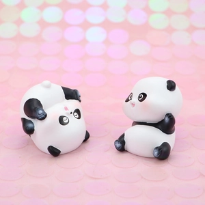 Close-up of two cute mini panda figurines with pink rosy cheeks on a glittery pink surface