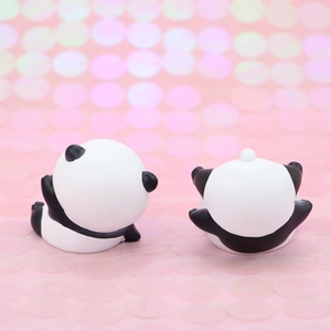 Close-up of two cute panda miniature figurines in lying poses for cake decoration
