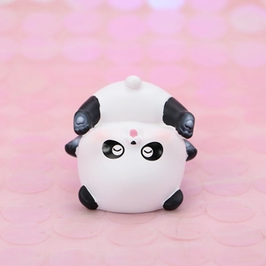 Close-up of a cute resin panda figurine with heart paw details on a pink glitter backdrop