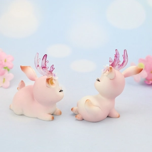 Close-up of pink resin deer cake toppers with glittery antlers and floral details