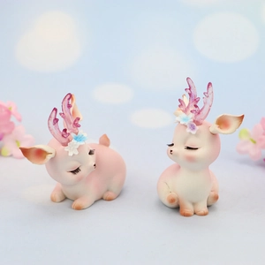 Close-up of cute pink resin reindeer cake topper with floral horns and dreamy blue background