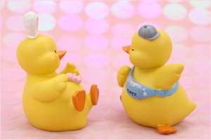 Detail of yellow duck figurines with rabbit ears and a Super crossbody bag on pink glitter