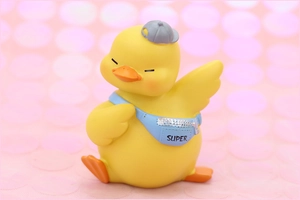 Macro view of cute yellow duck car ornament with blue super bag and grey sun hat