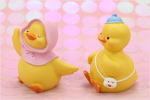 Detailed close-up of cute yellow resin ducks with pink and blue hats on a pink background
